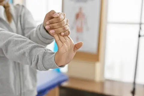 Person stretchar handleden för musarm behandling.