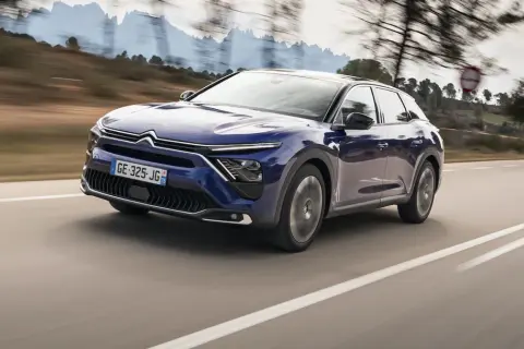 Granatowy Citroën C5 X, nowoczesny mpv, pędzi po krętej drodze wśród wzgórz.