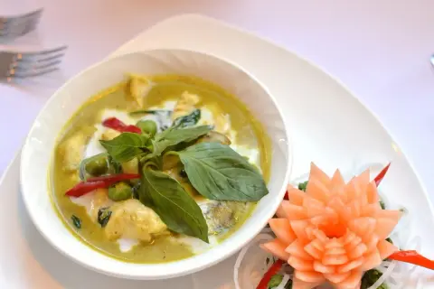 Zielony curry z kurczakiem, mleczkiem kokosowym i bazylią. Czy przyprawa curry jest ostra? Ten talerz sugeruje, że tak, dzięki czerwonym papryczkom chili.