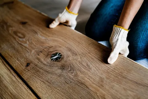 Ręce w rękawiczkach układają drewniane deski. Zastanawiasz się, jakie panele podłogowe wybrać? Ten naturalny wygląd może być inspiracją.