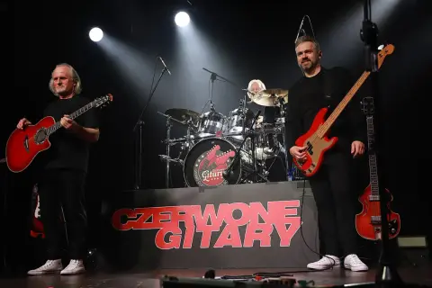 Czerwone gitary na scenie, jak jesienny deszcz dźwięków. Zespół gra, a na tle logo zespołu.
