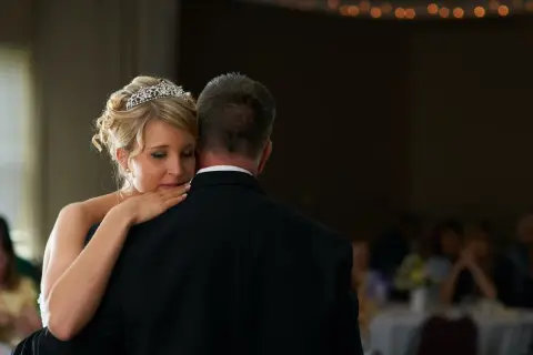 Ein zärtlicher Vater-Tochter-Tanz. Die Braut mit Diadem lehnt sich an ihren Vater, der einen schwarzen Anzug trägt.