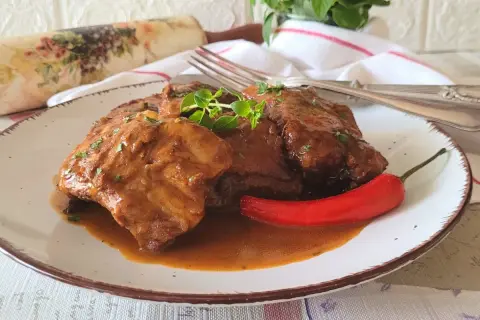 Pyszne, domowe babcine żeberka w sosie własnym, podane z ostrą papryczką i świeżymi ziołami.