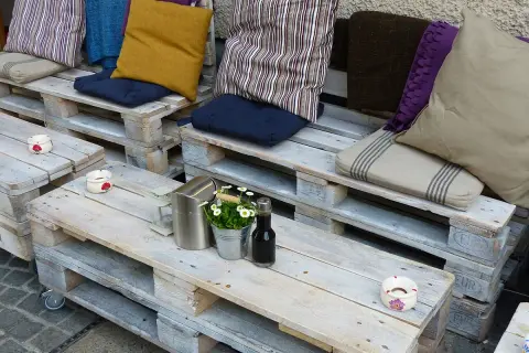 Un accogliente divano fai da te realizzato con pallet, decorato con cuscini colorati e un tavolino, perfetto per un angolo relax.