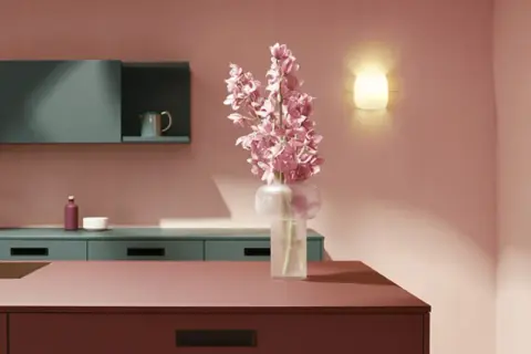 Elegante cocina con encimeras y armarios en tonos rosados y verde azulado. Un jarrón con flores rosas ilumina el espacio, creando una hermosa **combinación de colores para cocina**.