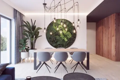 Nowoczesny salon z jadalnią, gdzie centralnym punktem jest okrągła ściana z zieleni i nietypowy żyrandol pajęczyna.
