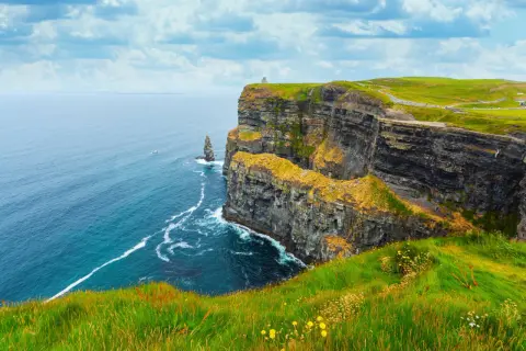 Skały w Irlandii, zielone wzgórza i błękitne morze. Przyjemna irlandia temperatura sprzyja spacerom po klifach.