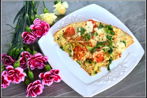 Pyszny omlet z tuńczykiem, pomidorami i zielonymi warzywami, udekorowany kwiatami.