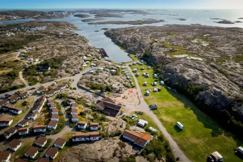 Vacker vy över Solvik first camp med stugor, husvagnar och lekplats vid havet.
