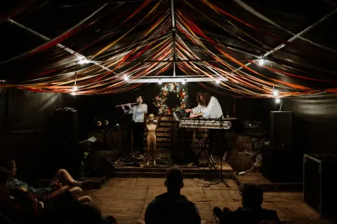 Muzycy grają na scenie pod kolorowymi wstążkami. Atmosfera jak na **grajdół festiwal**.