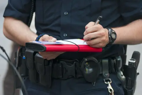 Policjant spisuje mandat. Dowiedz się, jak zapłacić mandat przelewem, by uniknąć dodatkowych kosztów.