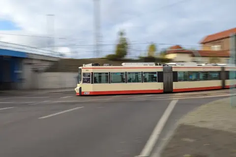 Ein langer, gelber und roter Straßenbahnzug fährt durch Wrocław. Mit jakdojade wrocław finde ich schnell die nächste Haltestelle.