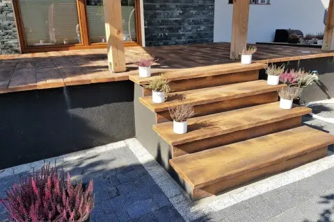Drewniane schody tarasowe z wrzosami w doniczkach. Idealne rozwiązanie co na podłogę na taras, dodające uroku.