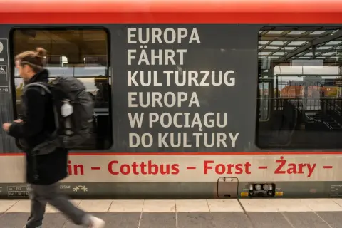 Ein Mann mit Rucksack steigt in einen Zug, der von Berlin nach Breslau fährt. Der Schriftzug "Europa fährt Kulturzug" ziert die Seite.