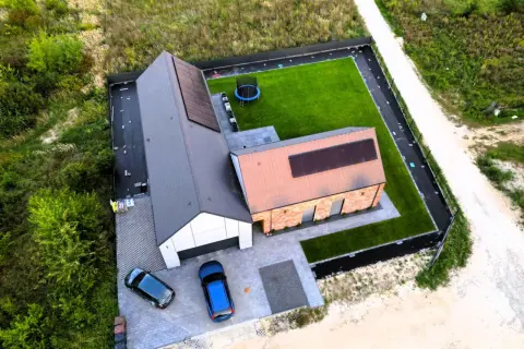 Nowy dom z panelami słonecznymi i zadbanym ogrodem. Zastanawiasz się, ile realnie kosztuje budowa domu?