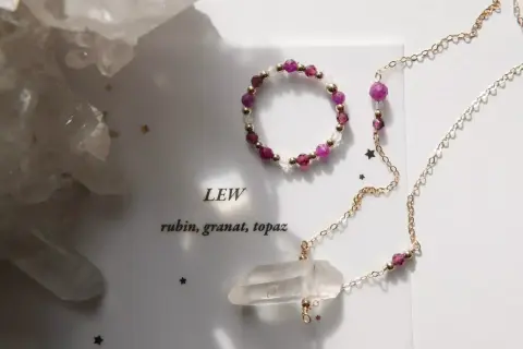 Jaki kamień dla Lwa? Rubin, granat i topaz w złotej biżuterii, obok kryształów.