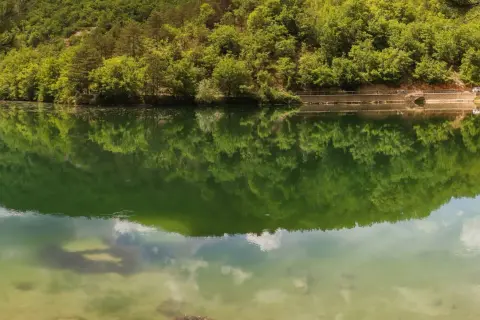 Verde smeraldo del lago di Boccafornace riflette la lussureggiante vegetazione che lo circonda, creando un'immagine speculare mozzafiato.