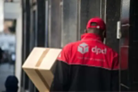 Kurier DPD z paczką przy drzwiach. Brak kodu odbioru na przesyłce.