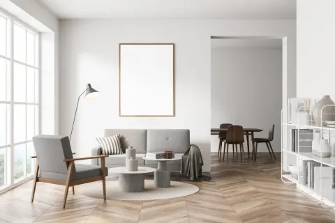 Nowoczesny salon z szarą kanapą i fotelem, stolikami kawowymi, lampą i pustą ramą na ścianie. Czy szary z beżem pasuje? Tak, tworzy przytulną atmosferę.