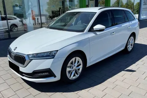 Białe, duże auto rodzinne typu kombi stoi przed salonem samochodowym. Idealne na wakacyjne wyjazdy i codzienne dojazdy.