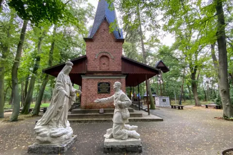 Kapliczka z figurami Matki Bożej i klęczącego mężczyzny. Warto zobaczyć po drodze do Lichenia, piękny las wokół.