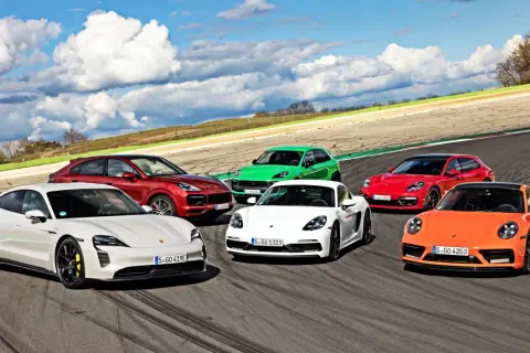 Kolekcja sportowych modeli Porsche: biały Taycan, czerwony Cayenne, zielony Macan, biały Cayman, czerwona Panamera Sport Turismo i pomarańczowy 911 na torze wyścigowym.