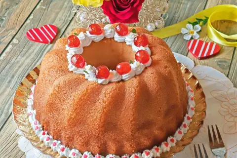 Un delicioso baba postre decorado con crema batida y cerezas rojas, listo para celebrar el amor.