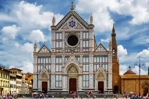 La magnifica facciata della Basilica di Santa Croce domina la piazza, con il cielo azzurro e nuvole bianche.