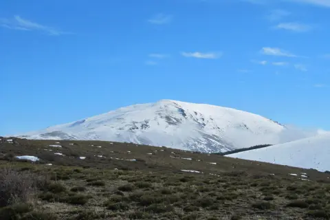 El pico más alto de Almería, cubierto de nieve, se alza majestuoso bajo un cielo azul despejado.
