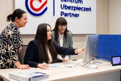 Trzy kobiety przy biurku analizują dane na komputerze.