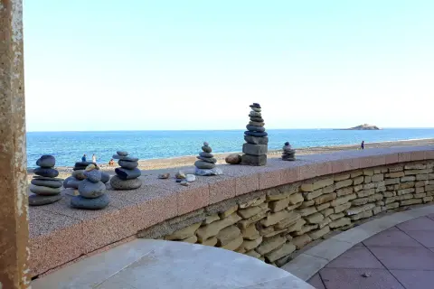 Torres de piedras en el **carboneras paseo marítimo**. El mar azul y el cielo despejado crean un fondo sereno para estas esculturas efímeras.