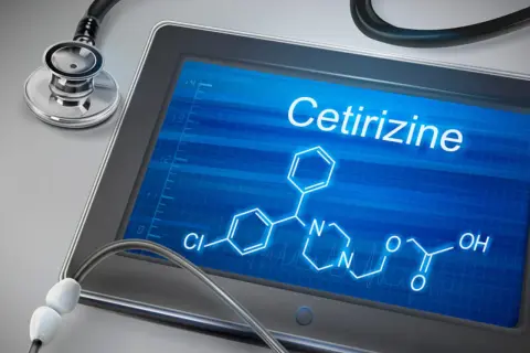 Tablet z ekranem wyświetlającym wzór chemiczny cetyryzyny i stetoskop.