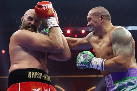 Two boxers clash in the highest weight class in boxing. Sweat flies as one lands a powerful punch, the other defends.