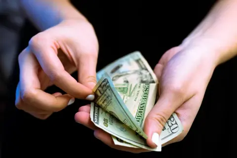 Dłonie liczą banknoty dwudziestodolarowe. Może to być związane z rozwiązaniem umowy o roboty budowlane za porozumieniem stron wzór.
