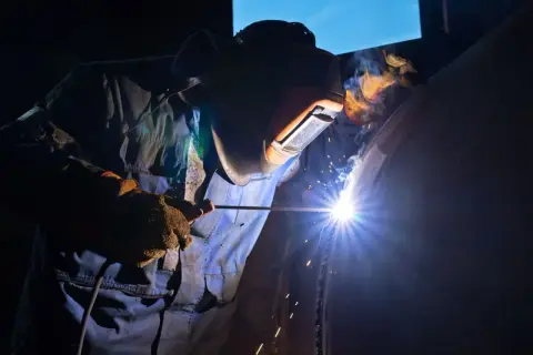 Spawacz w masce ochronnej spawa rurę, używając elektrody. Zastanawiasz się, jaka elektroda do stali 2mm?