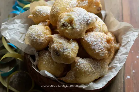 Frittelle di una volta, dolci e soffici, cosparse di zucchero a velo, in un cesto con coriandoli.