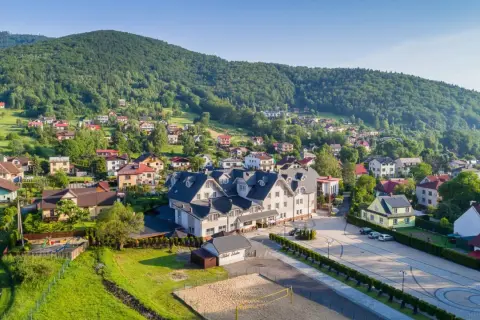 Widok na Hotel Skalite Spa & Wellness w Szczyrku, otoczony zielonymi wzgórzami i malowniczą zabudową.