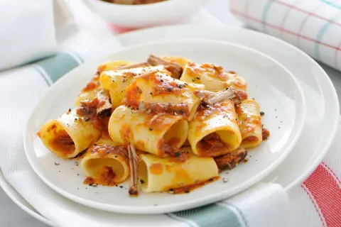 Une assiette de paccheri généreusement nappés d'une sauce tomate riche et de morceaux de viande savoureux. Ce plat de pâtes à la viande est un délice réconfortant.