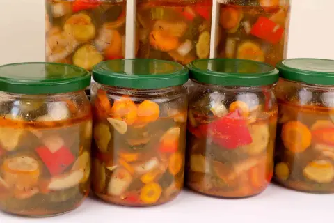 Słoiki pełne ogórków w przyprawie gyros, z dodatkiem papryki i marchewki.