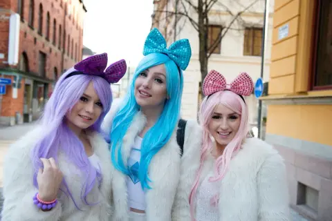 Alexandra Salomonsson och hennes vänner, klädda i pastellfärger och fluffiga pälsjackor, ler mot kameran på en svensk gata.