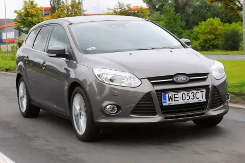 Szary Ford Focus MK3 1.6 benzyna w wersji kombi jedzie po drodze.