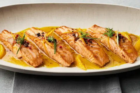 Gebratene Lachsfilets auf einer Zitrussoße, garniert mit Dill und Orangenzesten. Tolle Ideen für eine Fischplatte!