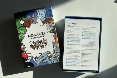 Pudełko gry fabularnej "Nosacze" z kolorowymi ilustracjami i otwartą instrukcją.
