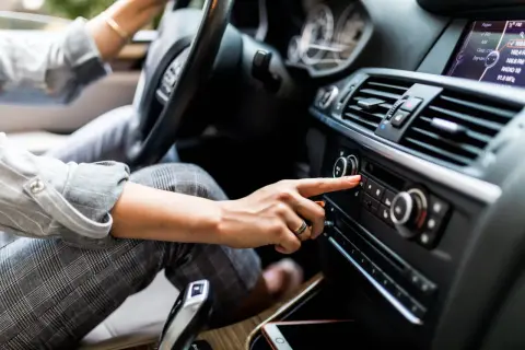 Une main ajuste le volume du radio qui grésille dans la voiture, cherchant la station parfaite pour le trajet.