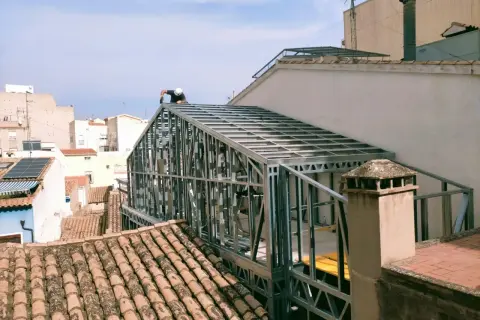 Un trabajador instala un tejado de steel framing sobre un edificio.