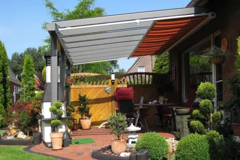 Moderne Terrassenbeschattung Ideen: Eine elegante Pergola mit ausfahrbarem Markisen-Dach schützt die gemütliche Sitzecke im Garten.