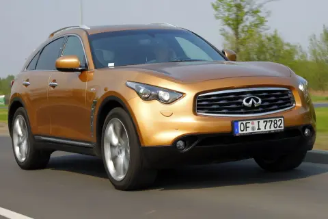 Złoty Infiniti FX35 pędzi po drodze, jego sylwetka jest dynamiczna i sportowa.