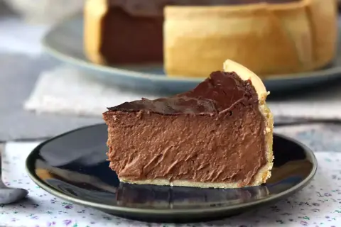 Rebanada de flan de chocolate con cobertura brillante, servida en plato oscuro.