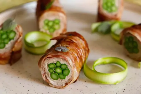 Deliziosi involtini di carne con asparagi freschi, avvolti in pancetta croccante e guarniti con erbe aromatiche.
