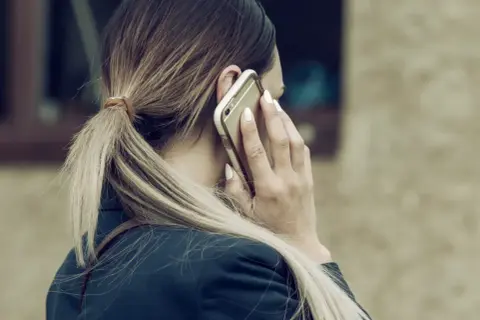 Kobieta rozmawia przez telefon, martwiąc się, czy pracodawca może odmówić urlopu na żądanie.
